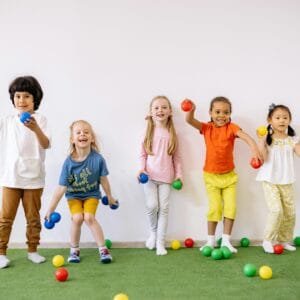 Happy diverse children playing with colorful balls indoors, showcasing fun and friendship.